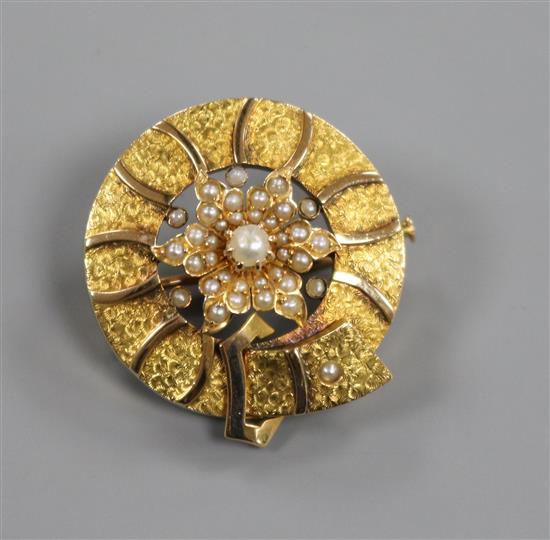 A yellow metal and seed pearl set circular belt and flower head brooch, 25mm.